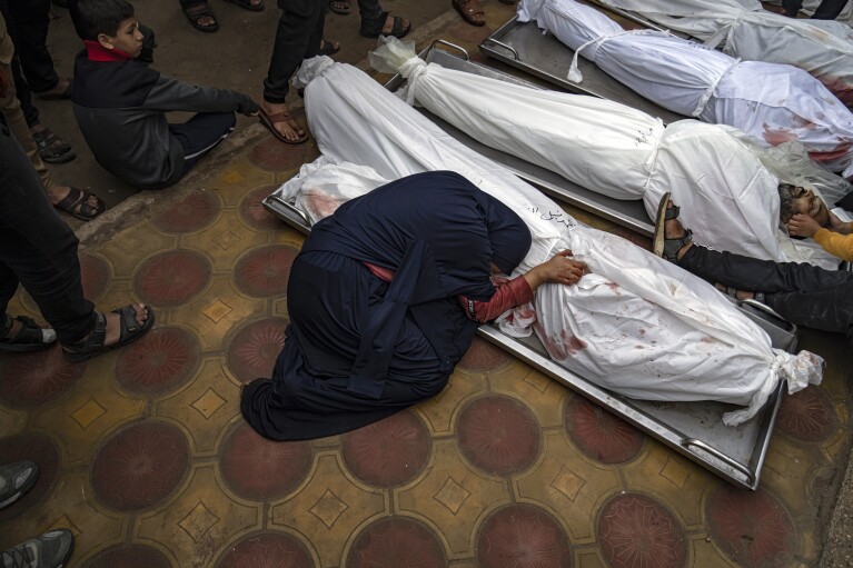 FILE - A woman mourns the covered bodies of her child and her husband killed in an Israeli army bombardment of the Gaza Strip, in the hospital in Khan Younis on Dec. 5, 2023. (AP Photo/Fatima Shbair, File)